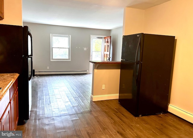 kitchen with baseboard heating, dark hardwood / wood-style flooring, and black refrigerator