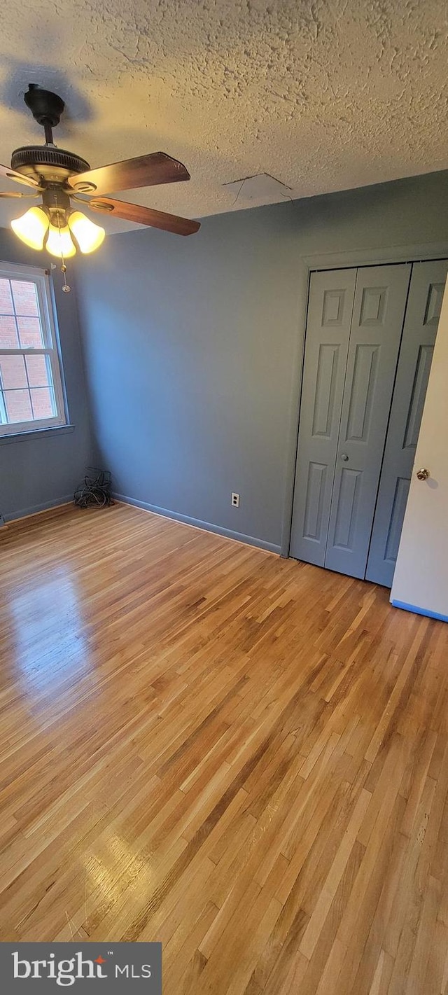 unfurnished bedroom featuring ceiling fan, a textured ceiling, light wood-type flooring, and a closet