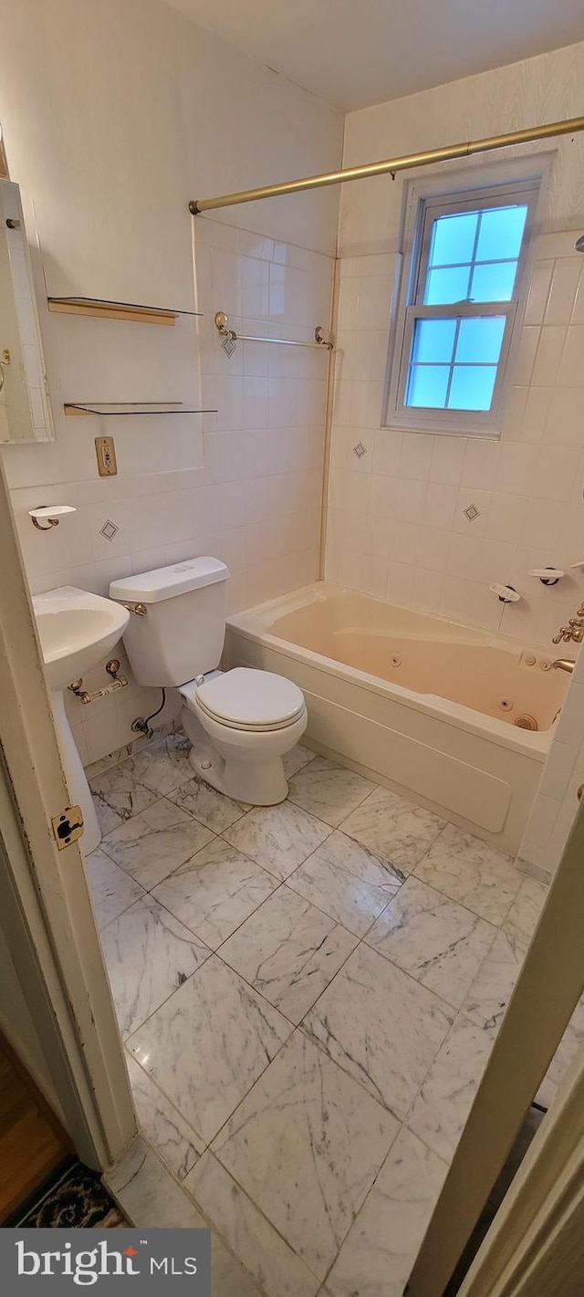 full bathroom with sink, tile walls, tiled shower / bath combo, and toilet