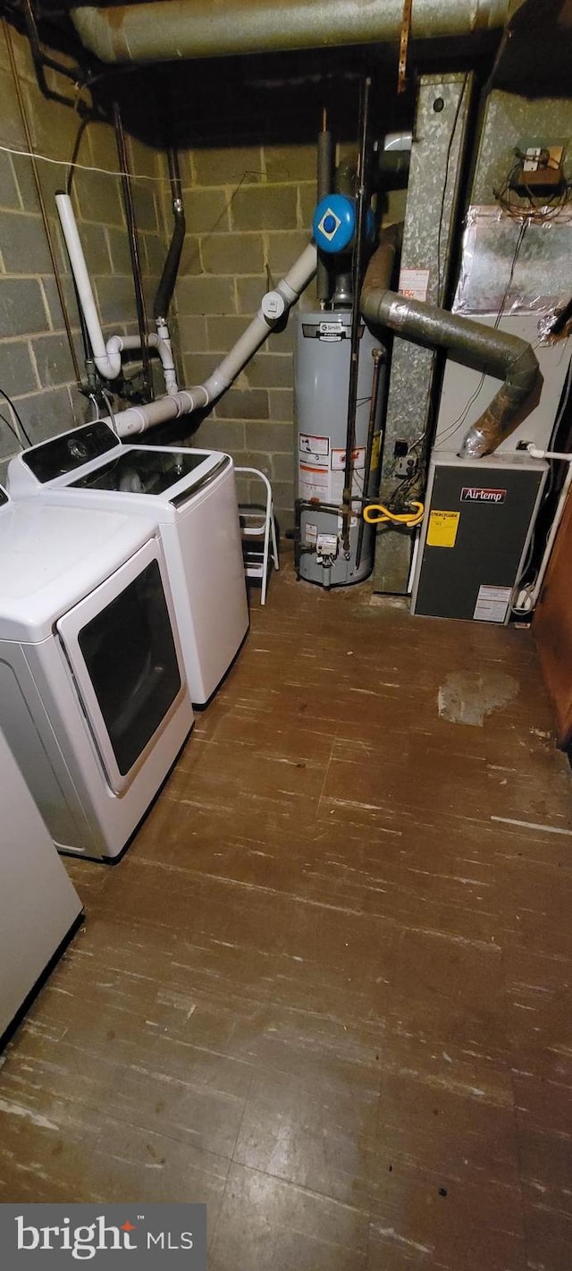 clothes washing area with water heater, separate washer and dryer, heating unit, and hardwood / wood-style flooring