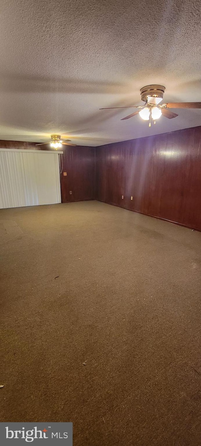 spare room featuring a textured ceiling and wood walls