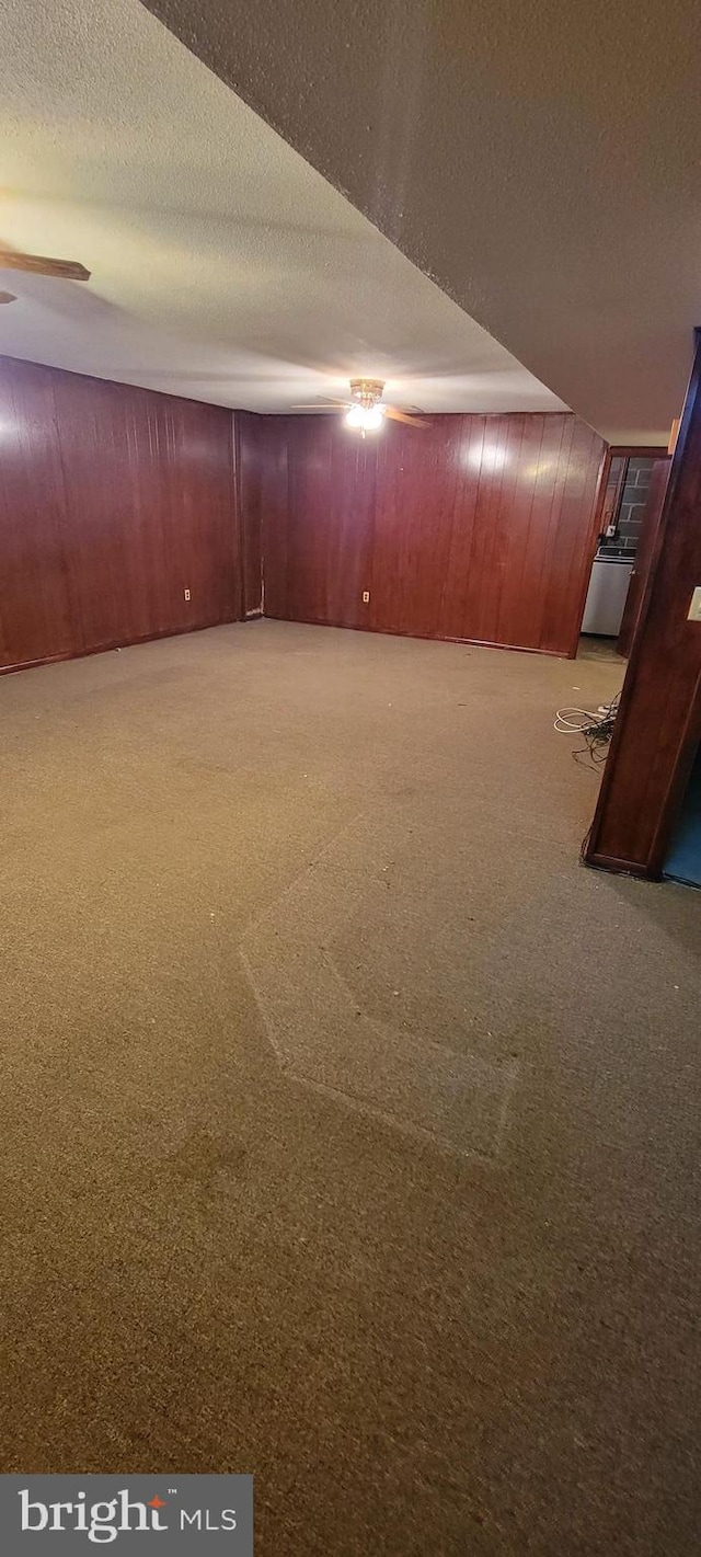 basement with wooden walls, a textured ceiling, and carpet floors