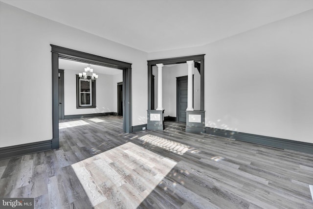 unfurnished room with wood-type flooring, a chandelier, and a wood stove