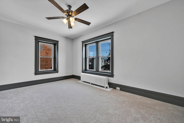 carpeted empty room with ceiling fan and radiator heating unit