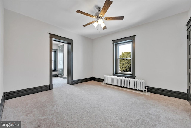 carpeted empty room with radiator heating unit and ceiling fan