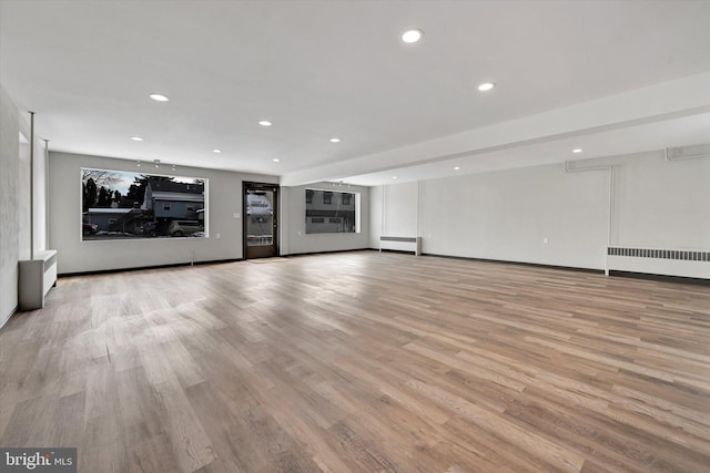 unfurnished living room featuring radiator, a baseboard radiator, and light hardwood / wood-style floors