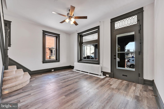 entrance foyer featuring hardwood / wood-style floors, ceiling fan, and radiator heating unit