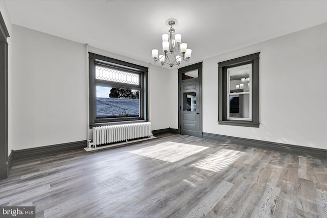 unfurnished room featuring radiator, a chandelier, and wood-type flooring