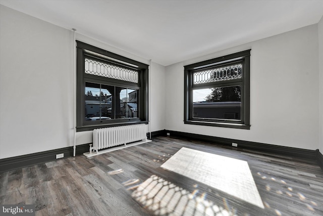 empty room featuring radiator heating unit and dark hardwood / wood-style floors