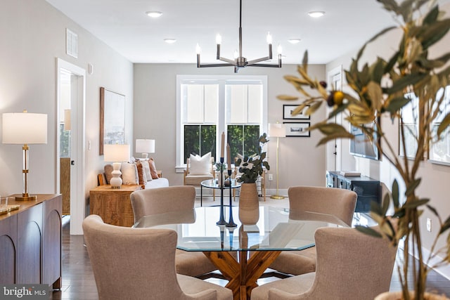 dining area featuring dark wood-type flooring and an inviting chandelier