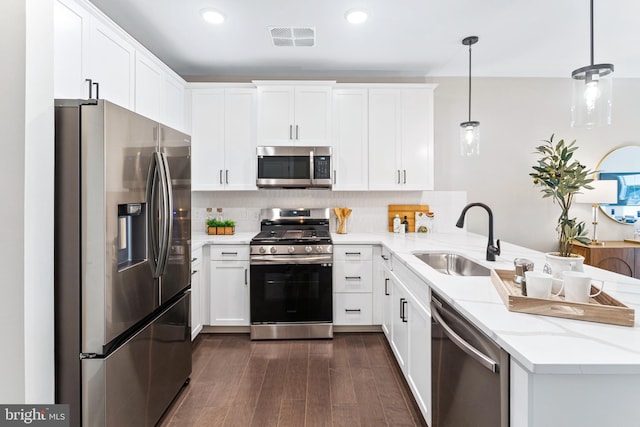 kitchen with a sink, stainless steel appliances, visible vents, a peninsula, and dark wood-style floors