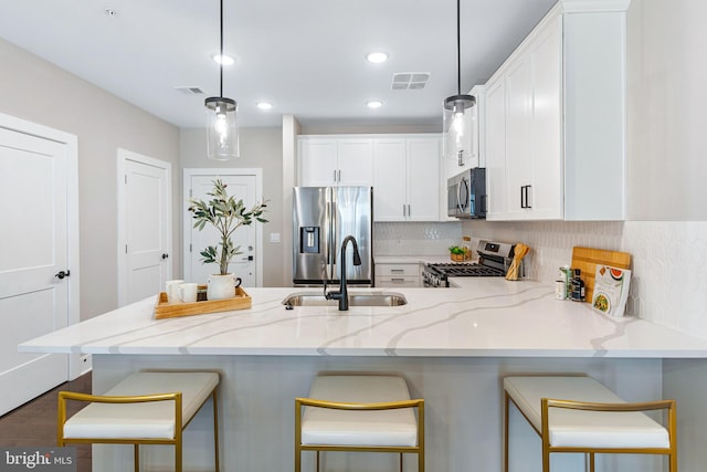 kitchen featuring light stone counters, white cabinets, decorative light fixtures, stainless steel appliances, and dark hardwood / wood-style flooring