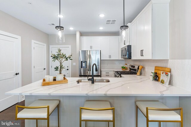 kitchen featuring stainless steel appliances, a peninsula, a sink, visible vents, and white cabinetry