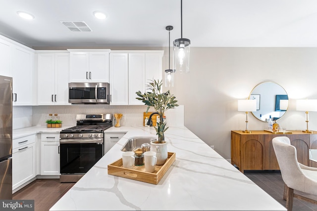 kitchen featuring decorative light fixtures, stainless steel appliances, light stone countertops, and white cabinetry