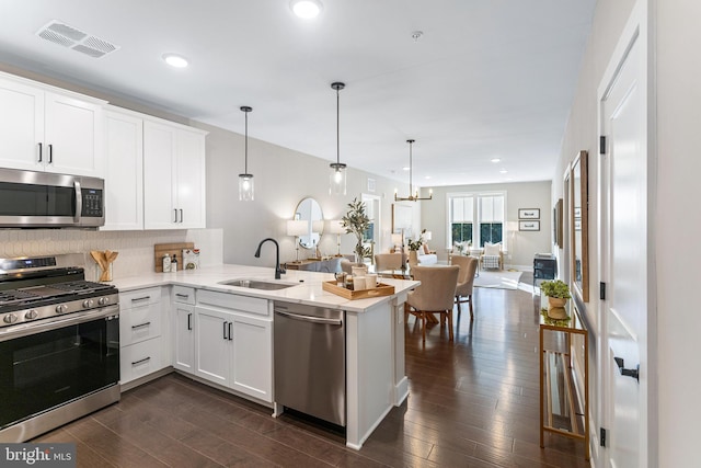 kitchen with pendant lighting, kitchen peninsula, white cabinets, and appliances with stainless steel finishes