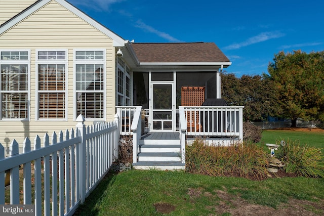 exterior space featuring a wooden deck, a yard, and a sunroom