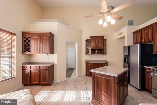 kitchen featuring dark brown cabinets, a center island, light tile patterned floors, appliances with stainless steel finishes, and ceiling fan