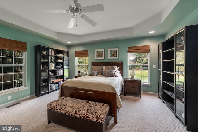 carpeted bedroom featuring a raised ceiling and ceiling fan