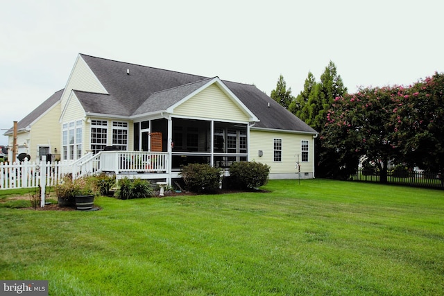 back of property with a deck, a yard, and a sunroom