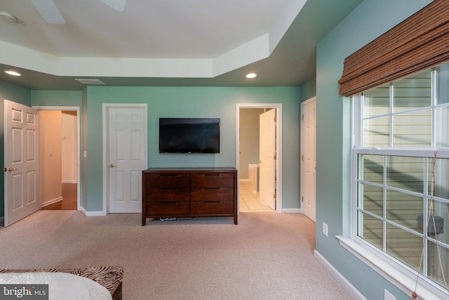 unfurnished bedroom featuring ensuite bathroom, light colored carpet, and ceiling fan