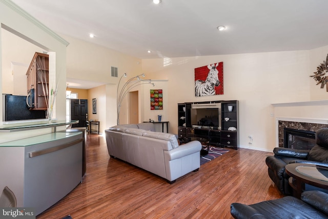 living room with lofted ceiling, a fireplace, and hardwood / wood-style floors