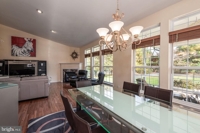 dining area with lofted ceiling, a high end fireplace, hardwood / wood-style floors, and a chandelier