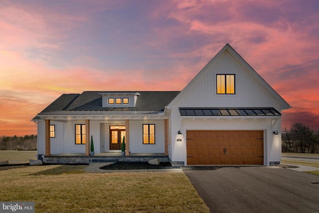 modern farmhouse style home featuring a garage, a yard, and covered porch