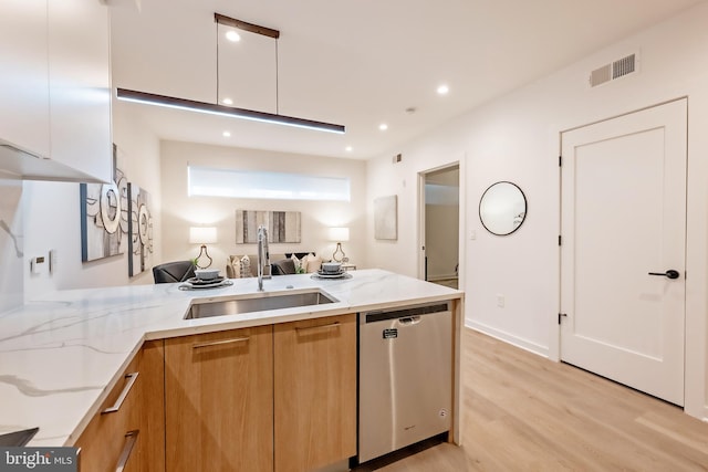 kitchen with light wood-type flooring, sink, stainless steel dishwasher, white cabinetry, and light stone countertops