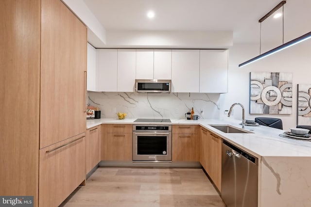 kitchen featuring light wood-type flooring, sink, stainless steel appliances, backsplash, and white cabinets