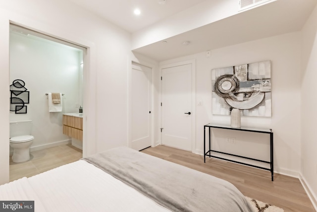 bedroom with light hardwood / wood-style flooring and ensuite bathroom