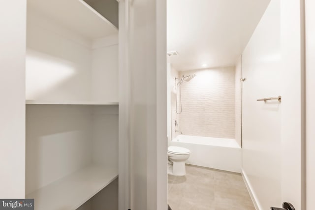 bathroom with tiled shower / bath combo, toilet, and tile patterned floors