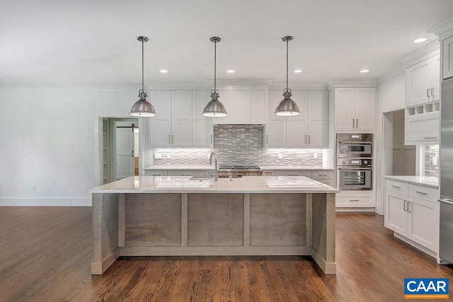 kitchen with appliances with stainless steel finishes, white cabinetry, dark wood-type flooring, an island with sink, and decorative light fixtures