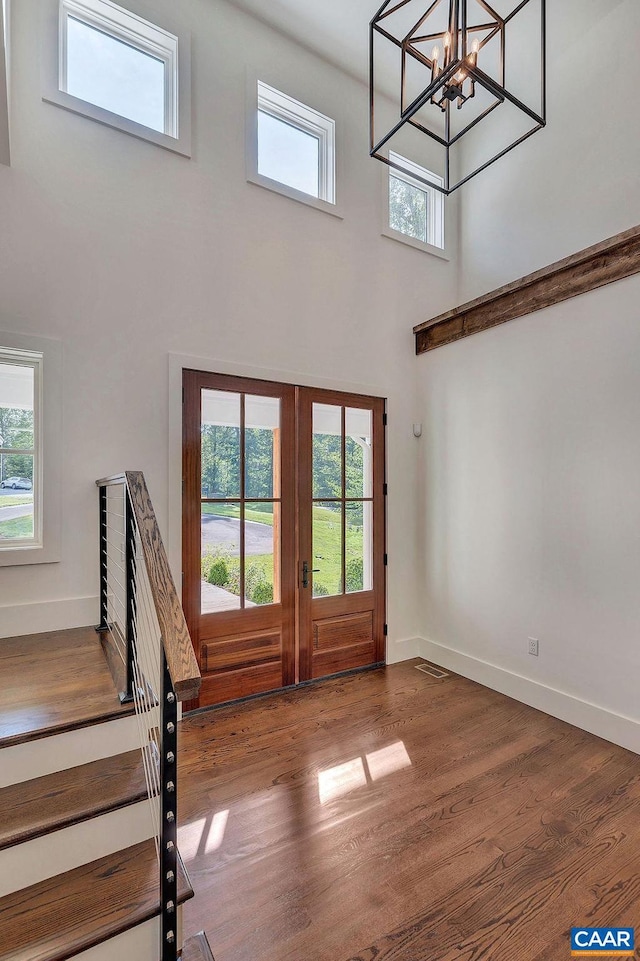 interior space with a wealth of natural light, a chandelier, a high ceiling, and hardwood / wood-style floors