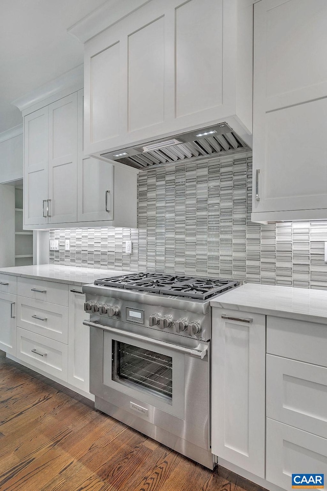 kitchen featuring stainless steel range, dark hardwood / wood-style floors, white cabinets, and decorative backsplash