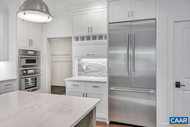 kitchen featuring light stone counters, white cabinets, dark wood-type flooring, stainless steel appliances, and decorative backsplash