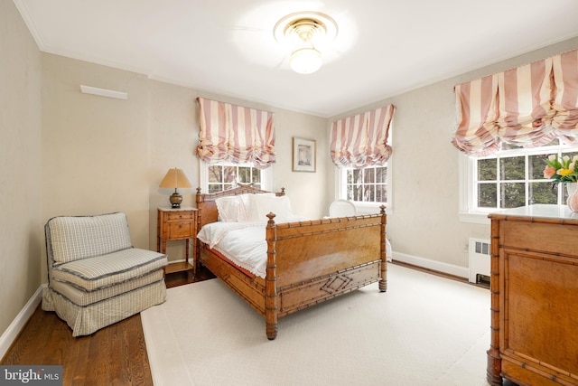 bedroom featuring hardwood / wood-style flooring, radiator heating unit, and crown molding