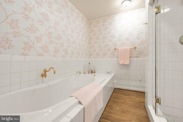 bathroom featuring tile walls, a bath, and hardwood / wood-style flooring