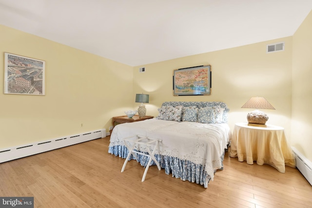 bedroom with wood-type flooring and a baseboard heating unit