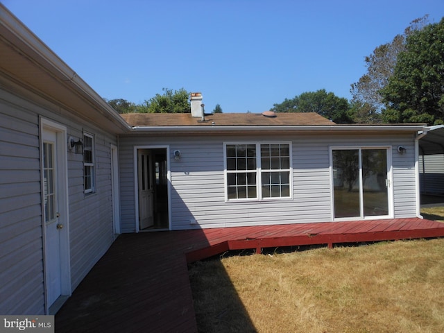 back of house featuring a lawn and a deck