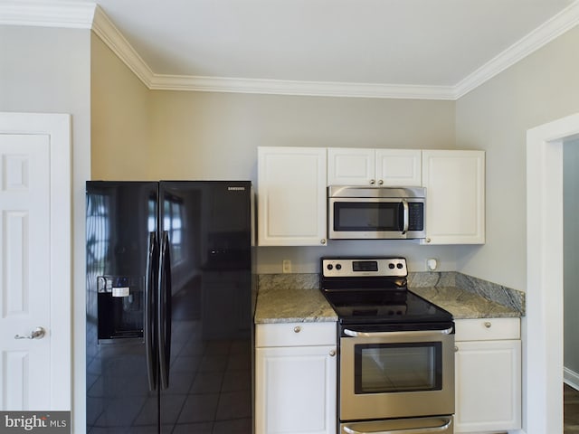 kitchen with dark tile patterned floors, white cabinetry, appliances with stainless steel finishes, dark stone countertops, and crown molding