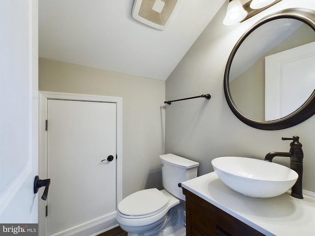 bathroom with vaulted ceiling, toilet, and vanity