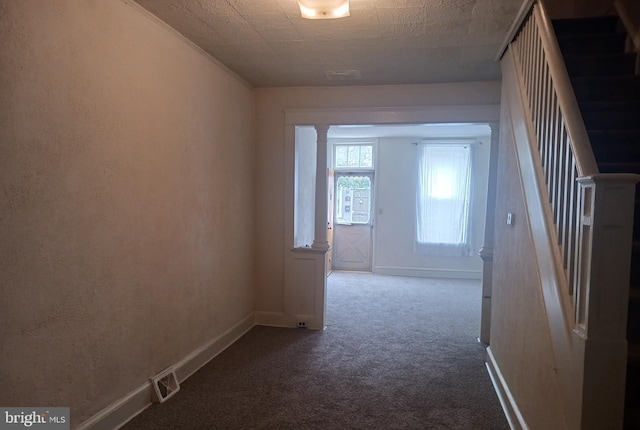 hallway with stairs, dark colored carpet, and baseboards