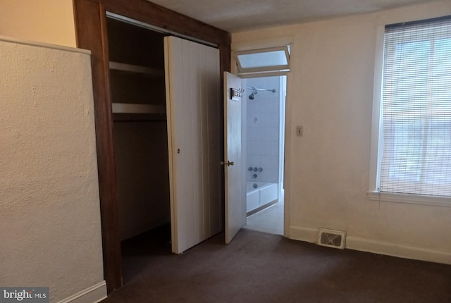 unfurnished bedroom featuring dark colored carpet and a closet