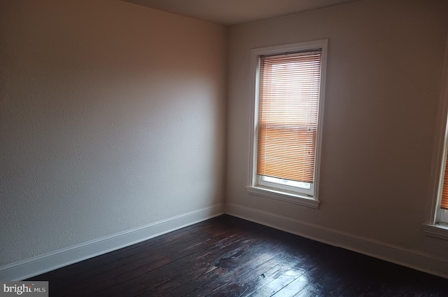 spare room featuring dark wood-style flooring and baseboards