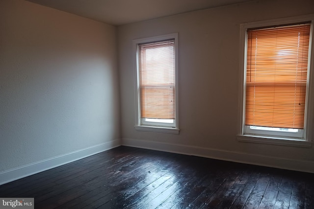 spare room with dark wood-type flooring and a healthy amount of sunlight