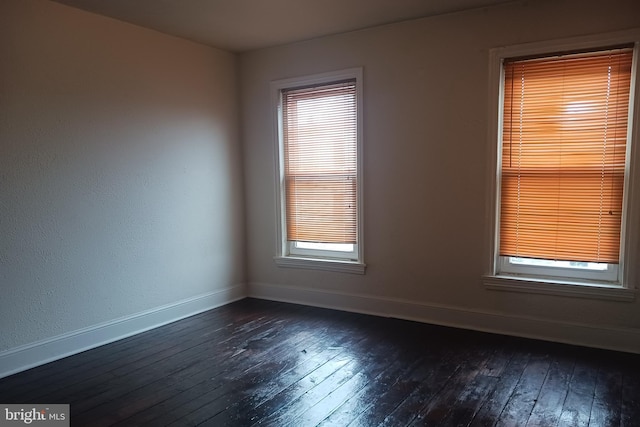 unfurnished room featuring baseboards and dark wood finished floors
