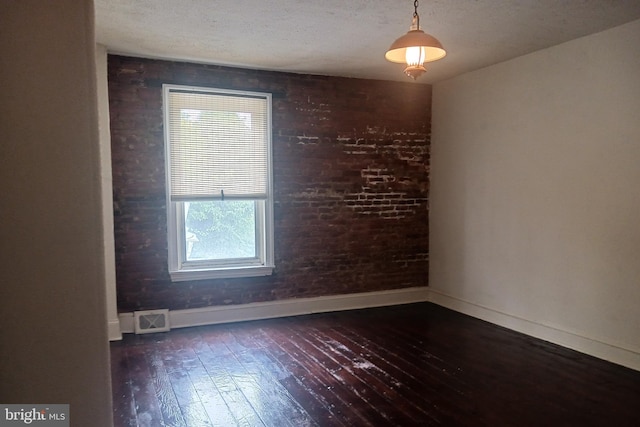 empty room with hardwood / wood-style floors, a textured ceiling, baseboards, and visible vents