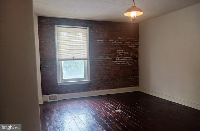 unfurnished room featuring wood-type flooring, a textured ceiling, baseboards, and visible vents