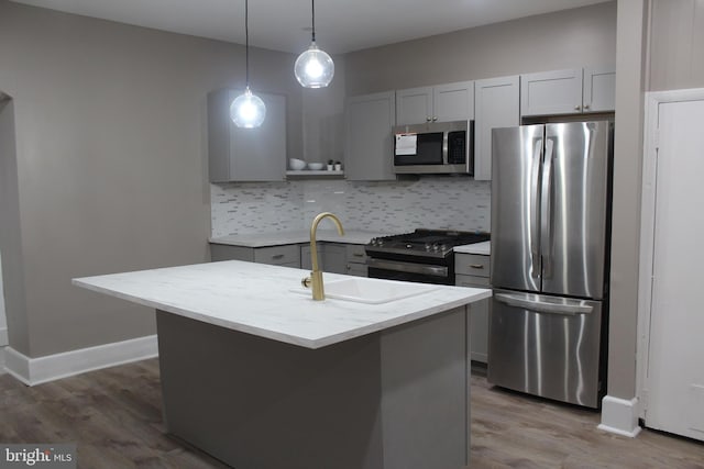 kitchen with decorative backsplash, a center island with sink, stainless steel appliances, and hanging light fixtures