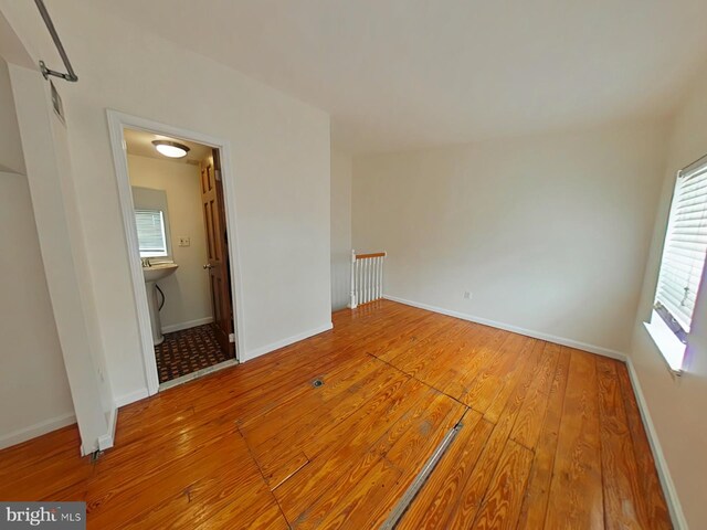 unfurnished room with wood-type flooring, sink, and a wealth of natural light